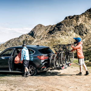 People putting bicycles on car bicycle rack