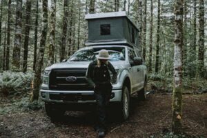 person and truck with overlanding accessories in forest